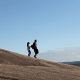 Hikers descending the granite slope trail on Enchanted Rock